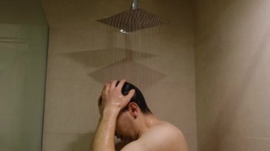 An upset angry man in a shower screaming and learning against a glass. Concept of depression and anger due to the stress, Shower as a place for emotional discharge