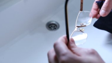 Cleaning glasses with microfiber. A man wipes his glasses with a black cloth. Selective focus. Concept of care of glasses.