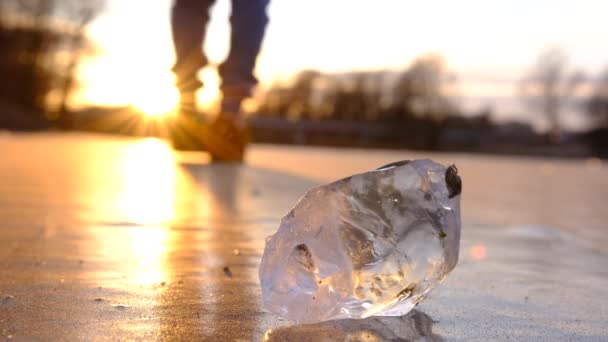 日没時に凍結した川を歩く青白い男の孤独な姿は 前方に氷の平和と 太陽の反射 — ストック動画