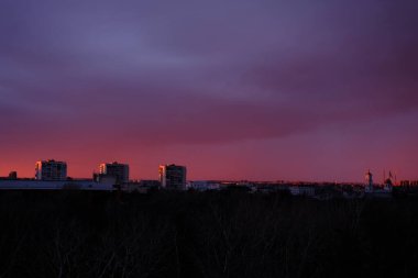 Sunset sky with city in the shadow background and red tones of the clouds.