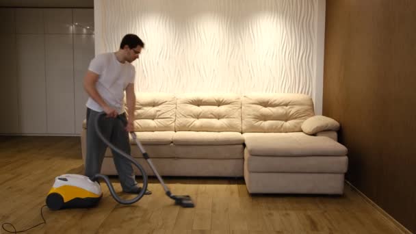Caucasian Handsome Serious Young Man Vacuuming Floor Cleaning Modern Apartment — Stock video