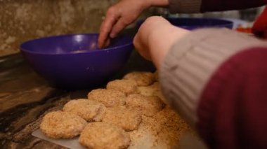 Old senior woman hands cooking cutlets on the kitchen. Homemade cutlets from the grandmother from meat in ruskes.