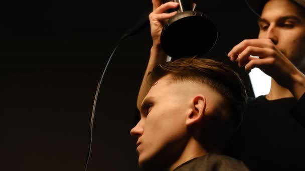 Young Barber Drying Hair Customer Hair Dryer Barber Shop Dark — Stockvideo