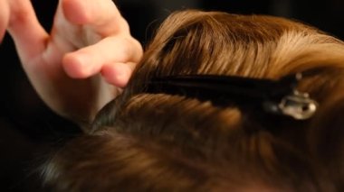 Closeup View Of barber using hair clip to fix the hair for cut and styling it. Hairdresser use pinsn hair salon. service in a modern barbershop in a dark key lightning with warm light Slow motion.