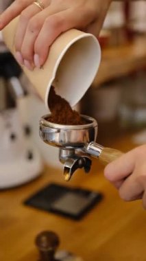 Profesyonel barista işçisi kahve dükkanında sıcak içecek yapmak için taze kahve çekirdeği döker..