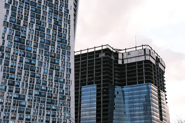 Şehirdeki gökyüzüne karşı inşaat alanı tarafından modern ofis binasının düşük açılı görüntüsü.