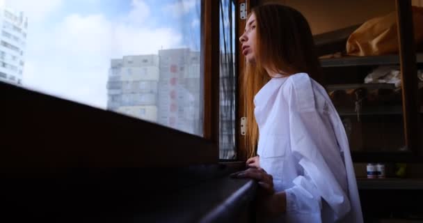 Jovem Ruiva Mulher Camisa Branca Olha Para Fora Janela Varanda — Vídeo de Stock