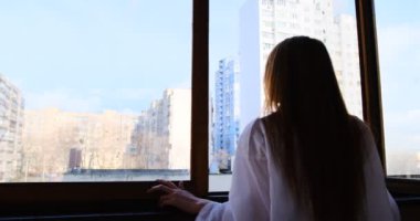 Beyaz tişörtlü genç kızıl kadın Pencereden dışarı bakıyor. Derin düşüncelere dalmış, kızıl saçlı, kızıl saçlı kız..