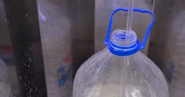 Yerel su filtresi istasyonunda otomatik su filtresi makinesi olan 5 litrelik plastik su şişesiyle suyu doldur..