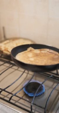 Genç bir kadın krep pişiriyor. Yakın plan. Gözlemeyi çevirir parmakları eski biege ocağında.