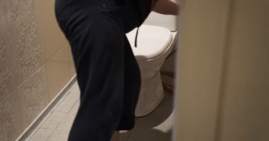 Yaşlı yaşlı yaşlı kadın tuvalette fayans döşemesini paspas ile yıkıyor, orta boy. Yaşlı kadın evdeki tuvaleti turuncu bezle temizliyor..