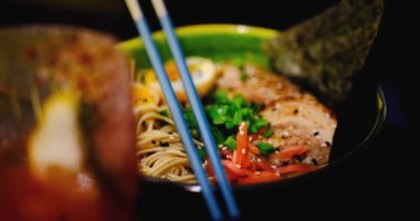 Lezzetli bir kase ramen üzerine mavi çubuklar. İçinde havuç, yosun, erişte, yumurta, et var. Yakın çekim zengin, besleyici çorbayı yakalar, yemek tutkunları için mükemmel bir aşçılık ilham kaynağıdır..