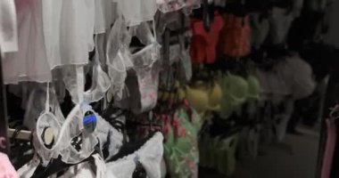 Kadın mağazadaki güzel dantel iç çamaşırlarına hayrandır. Özel kıyafetlerin cazibesini dikkatle inceler. Zarif tasarımları gösterir..