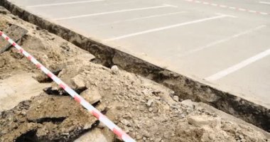 Kırmızı ve beyaz şeritli güvenlik bandıyla işaretlenmiş yeni kazılmış bir siper. Olay yerinde aktif inşaat çalışmaları ve güvenlik tedbirleri vurgulanırken, kentsel kalkınma devam ediyor