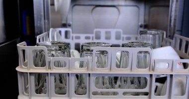 Siyah eldivenli bir bulaşık makinesi, mutfak ortamındaki hijyen ve güvenliği vurgulayan bulaşık makinesinden temiz bir tabağı kaldırır. Temiz gıda güvenliği ve profesyonel hizmet standartlarına odaklanır..