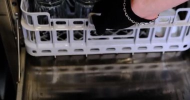 Bulaşık makinası iş başındayken endüstriyel bulaşık makinesinden yeni temizlenmiş bir tepsiyi kaldırıyor. Mutfak ortamındaki temizlik ve hijyenik ortam restoran için ideal..