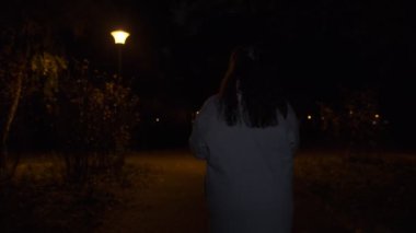 Gri paltolu kadın karanlık parkta yürür ve arkasına bakar. Aniden korkmaya başlar ve kamera onu gece atmosferinde takip eder. Kaçış sahnesinden korkar..