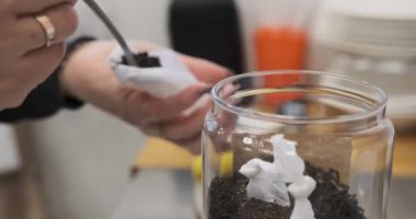 Dişi eller dikkatlice gevşek çayları demlemek için ayrı ayrı çay poşetlerine koyarlar. El işçiliğini vurgulayan hassas bir ambalaj sürecinin yakınlaştırılması