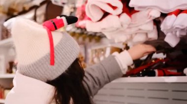 Kadın bayram havası için Noel bandı seçiyor, rahat bir ortamda dekoratif aksesuarları karıştırıyor, neşeli bir tatil ortamı yaratmak için mükemmel.