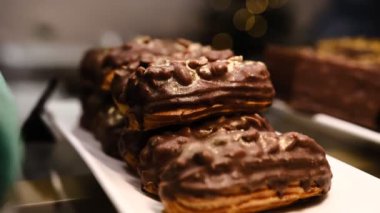 Lezzetli bir gurme, kremalı muhallebi ile doldurulmuş, üzerinde çıtır fıstıklar, zengin çikolata jölesi, ve lüks bir altın serpinti, görsel olarak çekici ve hoşgörülü bir tatlı yaratıyor.