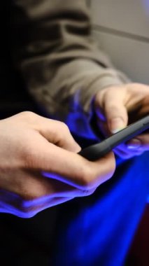 Hızlı parmak hareketleri ve renkli titreşimli el ışıkları ile mobil oyun oynayan genç adam, dinamik oyun, telefon ekranını kapat, dijital eğlence, oyun eylemi, enerjik oyun oturumu