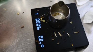 Porsiyon ve demleme hazırlığı için metal kabın içindeki gevşek çay yapraklarını tartmak yüksek kaliteli taze çay yapraklarını kapamak geleneksel çay yapma sürecini ölçmek için.