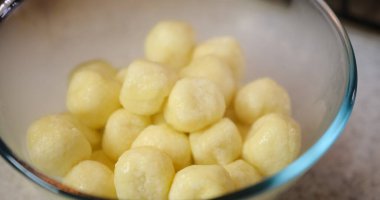 Buharlı cam kasede sıcak hamur köfteleri karıştırmak, granit arka planda ayarlanmış. Mutfak sahnesi, canlı renkler ve dokularla yemek hazırlama sürecini yakalar