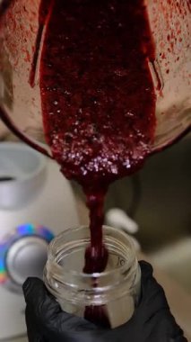 Frenk üzümü püresi karıştırıcı kavanozdan cam bir kavanoza dökülür. Saklama için pürüzsüz doku zengin doğal aromalar. Zenginleştirilmiş doğal aromalar...