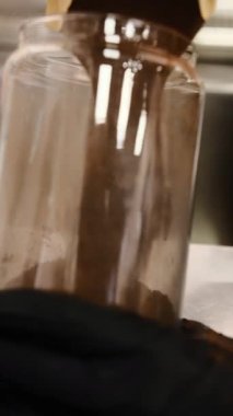 Doğal kakao, kağıt bir paketten şeffaf bir cam kavanoza dökülür. Kahverengi renkli, pürüzsüz organik malzemeler tatlı içecekleri ya da yemek tarifleri için mükemmeldir. Zarif bir depo.