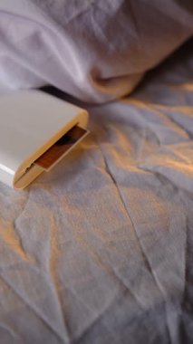 Minimalist tasarım, modern teknoloji, yaratıcı süreç, rahat atmosfer, taşınabilir kolaylık gibi konularla ilgilenen bir adamla, yatak izlerinin üzerinde küçük bir cep büyüklüğünde beyaz yazıcı.