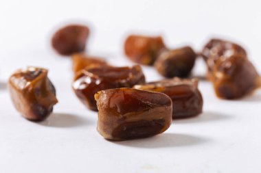 Beyaz arka planda doğranmış taze tarihlerin yakın çekimi, parlak dokularını, zengin kahverengi tonlarını ve doğal tatlılığını vurgulamak, sağlıklı yemek ve tatlı tarifleri için mükemmel.