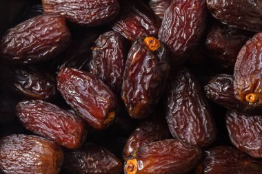 Taze Medjool tarihlerinin makro yakın çekimi, koyu parlak ciltleri, doğal kırışıklıkları ve zengin dokusu, sağlıklı besin ve beslenme temaları için mükemmel.