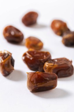 Beyaz arka planda doğranmış taze tarihlerin yakın çekimi, parlak dokularını, zengin kahverengi tonlarını ve doğal tatlılığını vurgulamak, sağlıklı yemek ve tatlı tarifleri için mükemmel.