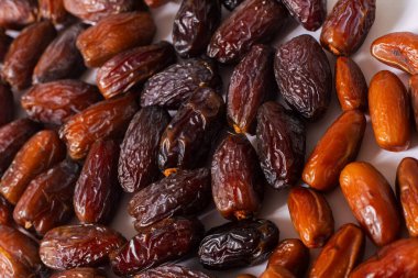 Beyaz zemin üzerinde çeşitli taze tarihler yakın plan, altın kahverengiden koyu kahverengiye farklı renkler ve dokular sergileniyor, sağlıklı yiyecek ve gurme kavramları için mükemmel.