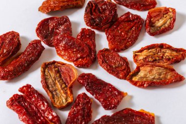 Beyaz zemin üzerine dizilmiş güneşte kurutulmuş domatesler canlı kırmızı renklerini ve doğal dokusunu vurguluyor. Akdeniz mutfağı ve gurme yemek kavramları için mükemmel.