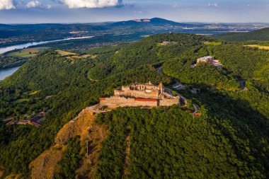 Visegrad, Macaristan - Viyana 'nın güzel yüksek şatosunun yaz yaprakları ve ağaçlarıyla hava aracı görüntüsü. Güneşli bir günde arkasında bulutlar olan Dunakanyar ve mavi gökyüzü