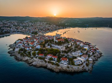 Primosten, Hırvatistan - Hırvatistan 'ın Dalmaçya kentinde güneşli bir yaz sabahında Primosten yarımadası ve eski kentin havadan manzarası. Adriyatik kıyılarında gün doğumunda mavi ve altın gökyüzü