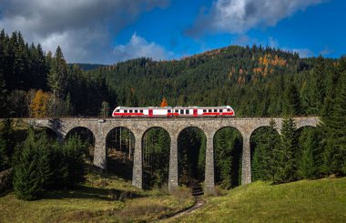 Telgart, Slovakya - alçak Tatra 'da güneşli bir sonbahar gününde mavi gökyüzü ve bulutlarla ünlü Chmarossky Viaduct. Normal tren viyadük boyunca gidiyor..