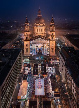 Budapeşte, Macaristan - Aydınlanmış St.Stephen Bazilikası 'ndaki Avrupa' nın en güzel Noel pazarının havadan görünüşü. Buz pateni pisti, Noel ağacı ve alacakaranlıkta açık mavi gökyüzü.