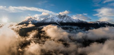Tatranska Lomnica, Slovakya - Yüksek Tatraların bulutların üzerindeki karlı tepelerinin hava panoramik manzarası, günbatımında High Tatras dağlarının en yüksek ikinci zirvesi olan Lomnicky Tepesi