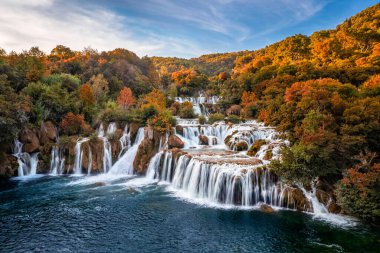 Krka, Hırvatistan - Krka Ulusal Parkı 'ndaki Krka Şelaleleri' nin güneşli bir sonbahar sabahı, gün doğumunda renkli sonbahar yaprakları ve mavi gökyüzü manzarası