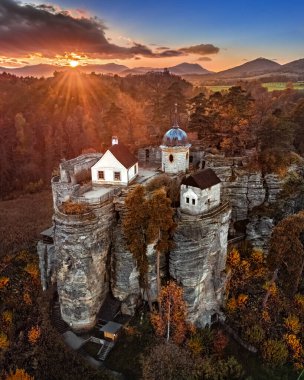 Sloup vs Cechach, Çek Cumhuriyeti - Kuzey Bohemya 'daki Rock Castle Sloup' un çarpıcı renkli bir günbatımı, bulutlar, mavi gökyüzü ve sonbahar yapraklarıyla havadan görünüşü