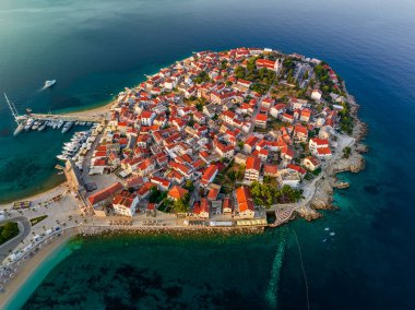 Primosten, Hırvatistan - Hırvatistan 'ın Dalmaçya kentinde güneşli bir yaz sabahında Primosten yarımadası, St. George Kilisesi ve eski bir kasabanın havadan manzarası. Yat marinası ve turkuaz deniz suyu Adriyatik deniz kıyısında gün doğumunda
