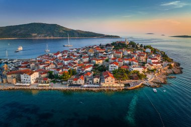 Primosten, Hırvatistan - Hırvatistan 'ın Dalmaçya kentinde güneşli bir yaz sabahında Primosten yarımadası ve eski kentin havadan manzarası. Adriyatik kıyılarında gün doğumunda mavi ve altın gökyüzü