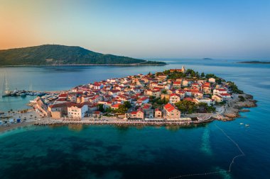 Primosten, Hırvatistan - Hırvatistan 'ın Dalmaçya kentinde güneşli bir yaz sabahında Primosten yarımadası ve eski kentin havadan manzarası. Adriyatik kıyılarında gün doğumunda mavi ve altın gökyüzü