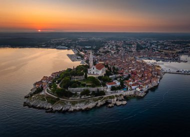 Rovinj, Hırvatistan - St. Euphemia Kilisesi ile eski Rovinj kasabasının havadan görünüşü ve Hırvatistan 'ın Istria kentinde bir yaz sabahı doğan güneş. Altın ve mavi gökyüzü ve Adriyatik Denizi kıyısındaki kırmızı çatılar