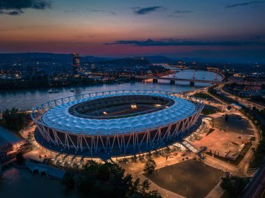 Budapeşte, Macaristan - Millî Atletizm Merkezi, Tuna Nehri üzerindeki Rakoczi köprüsü ve arkaplanda renkli günbatımı gökyüzüne sahip yeni gökdelen binası da dahil olmak üzere Budapeşte 'nin alacakaranlıkta havadan ufuk çizgisi