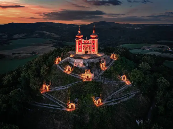 stock image Banska Stiavnica, Slovakia - Aerial view of the beautiful illuminated Baroque Calvary in Slovakia at dusk on a summer afternoon with dramatic colorful sky and clouds at background