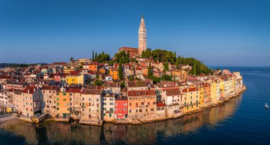 Rovinj, Hırvatistan - Hırvatistan 'ın Istria kentinde bir yaz sabahı St. Euphemia Kilisesi ile eski Rovinj kasabasının havadan panoramik manzarası. Açık mavi gökyüzü ve Adriyatik Denizi kıyısında ılık sabah ışıkları