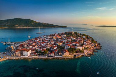 Primosten, Hırvatistan - Hırvatistan 'ın Dalmaçya kentinde güneşli bir yaz sabahında Primosten yarımadası ve eski kentin havadan manzarası. Yatlar, mavi ve altın rengi gökyüzü Adriyatik kıyılarının doğuşunda